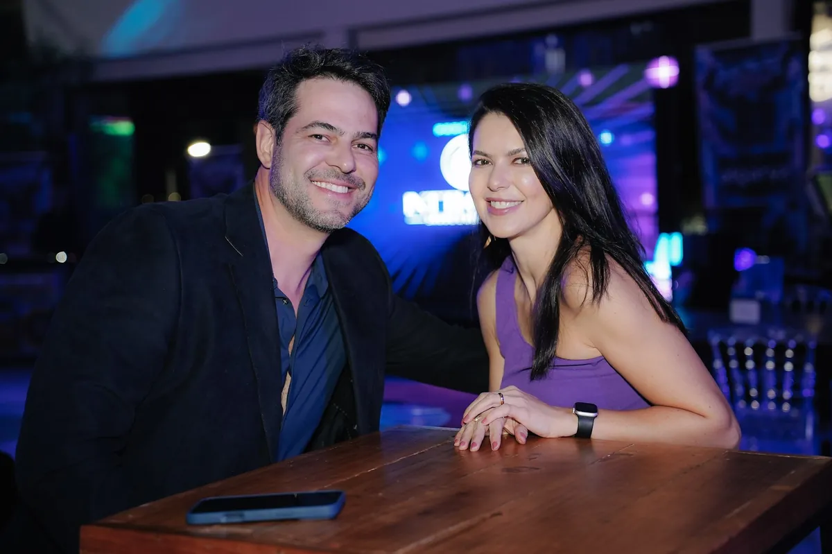Empresário e empresária sorrindo à mesa no MOVE Anos 2000